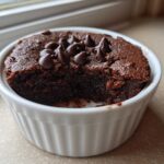 A rich, dark chocolate Cottage Cheese Microwave Brownie topped with chocolate chips, served in a white ramekin.