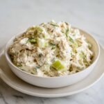 A close-up of creamy cottage cheese chicken salad mixed with celery chunks and topped with fresh dill.