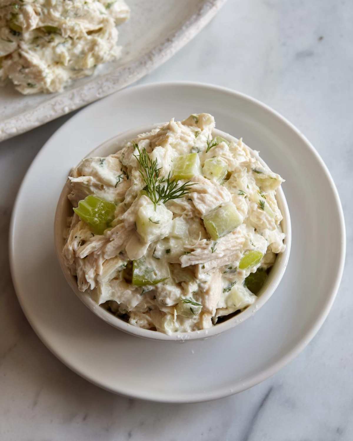A close-up of creamy cottage cheese chicken salad mixed with celery, served in a small white bowl.
