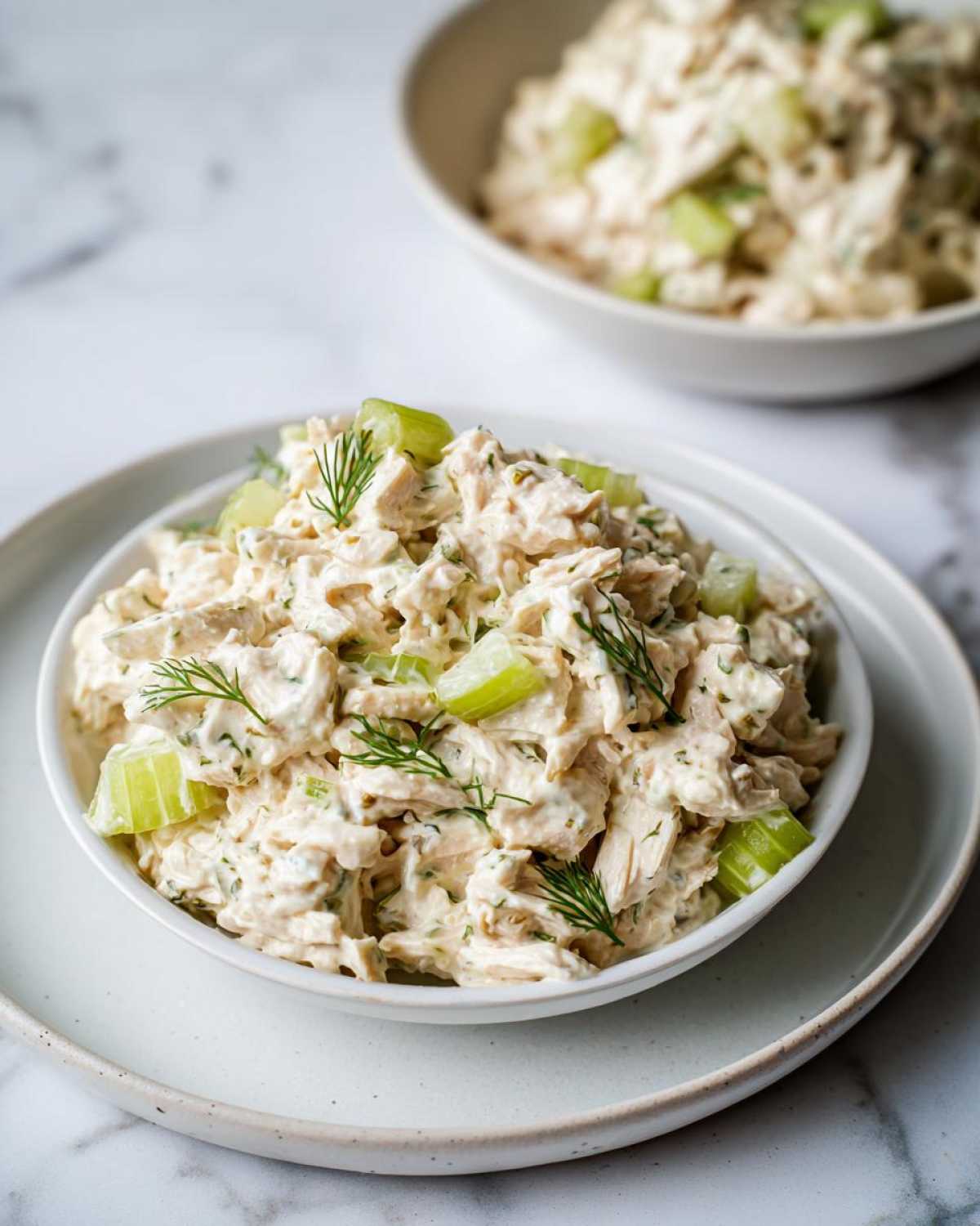 A close-up of creamy cottage cheese chicken salad mixed with celery chunks and topped with fresh dill.