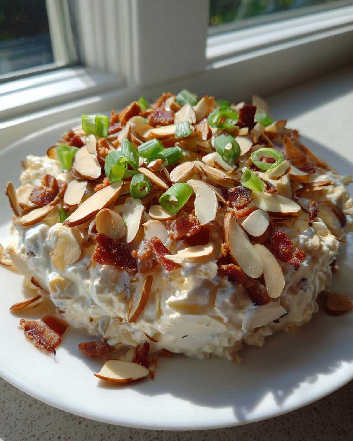 A mound of creamy Neiman Marcus dip generously topped with sliced almonds, crumbled bacon, and green onions.