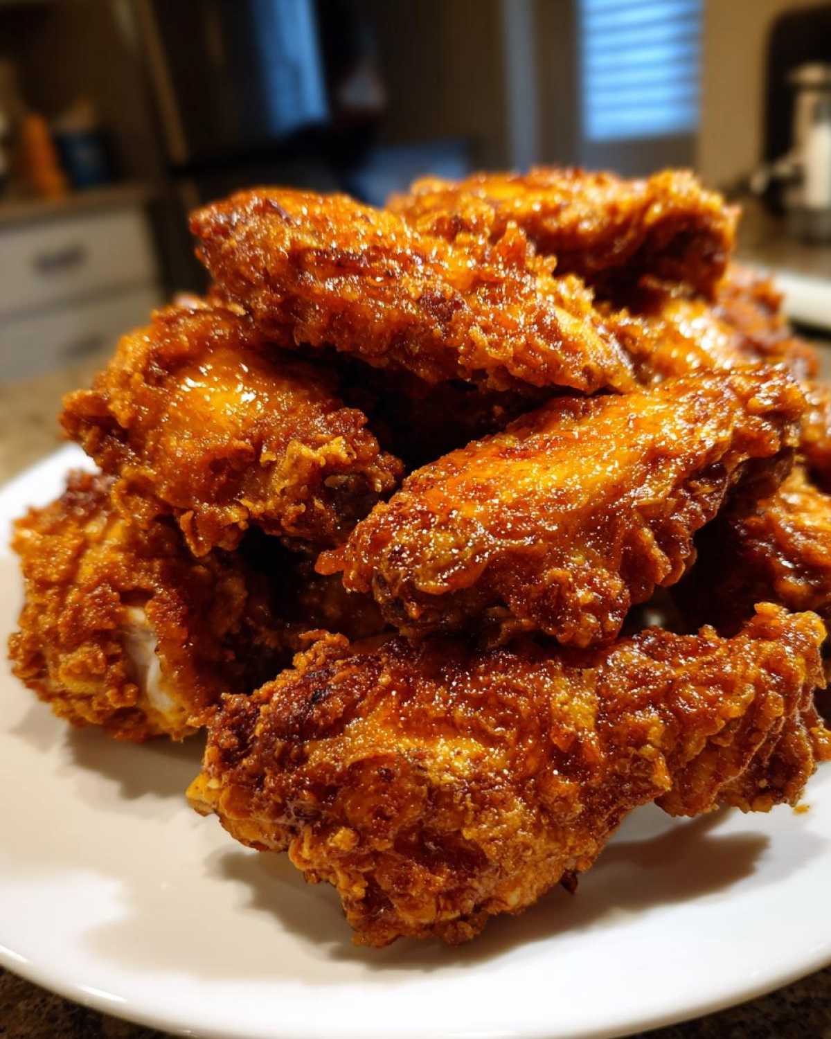 Close-up of a mound of golden-brown, crispy chicken wings coated in a shiny glaze.