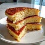 Close-up of stacked, sliced coconut flour pancakes showing their fluffy interior and golden-brown edges.