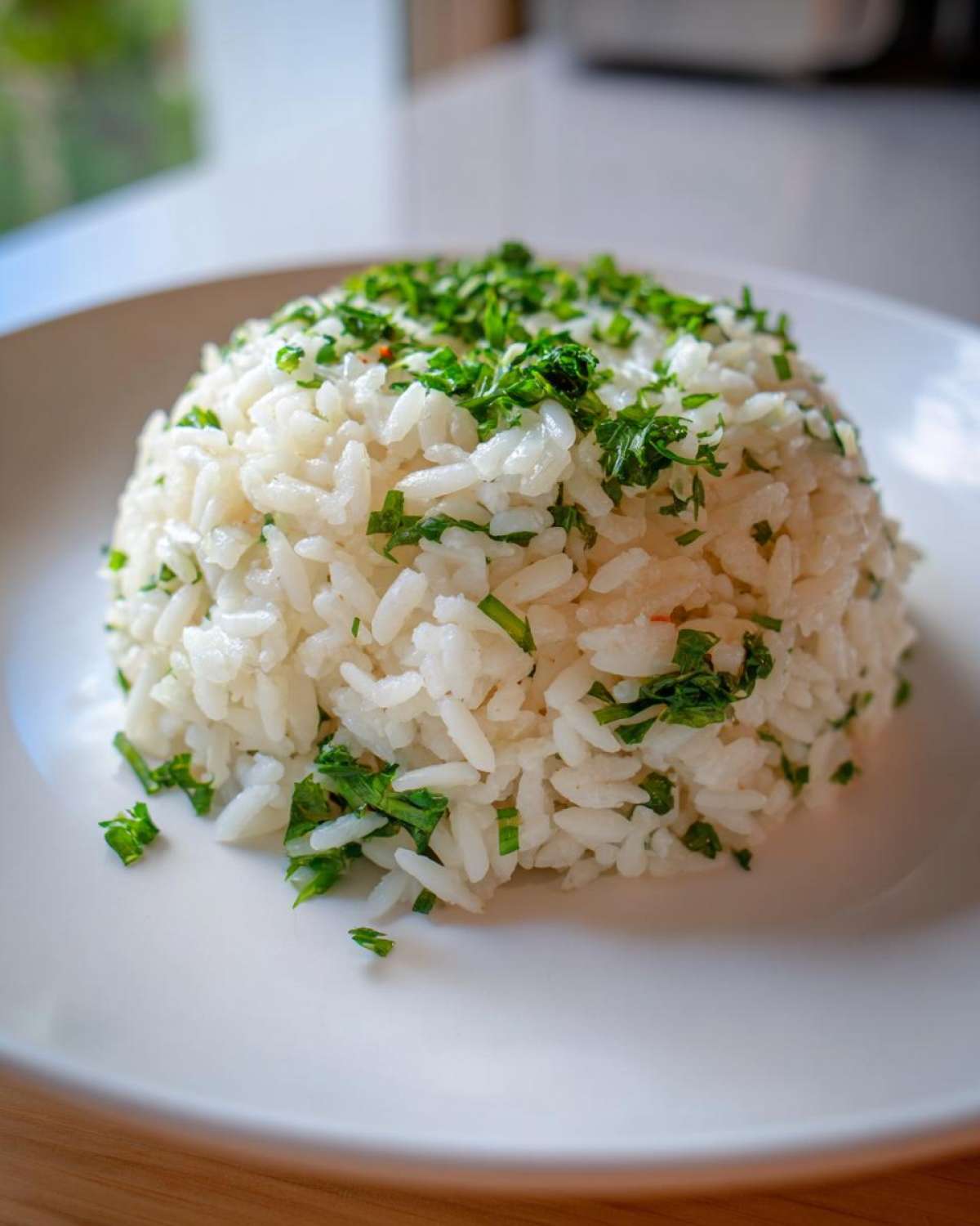 A perfectly molded mound of fluffy white rice pilaf topped generously with chopped fresh green herbs.