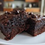 Close-up of two fudgy sweet potato brownies topped with melted chocolate chips on a white plate.