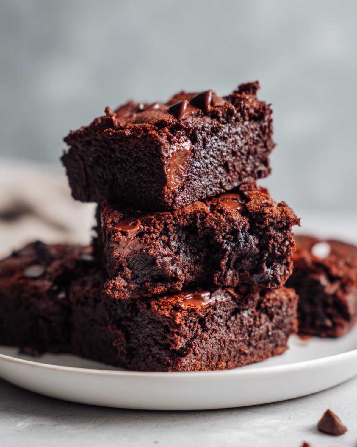Close-up of a stack of three fudgy sweet potato brownies topped with melted chocolate chips.