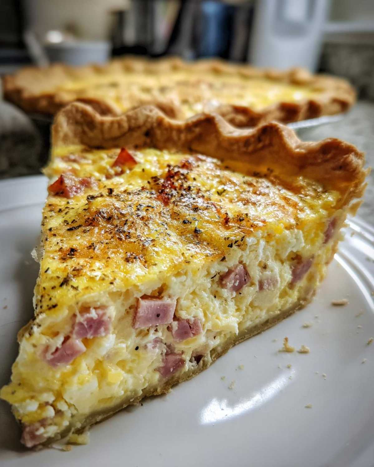 Close-up of a thick slice of Ham and Cheese Quiche showing chunks of ham in the creamy egg filling.