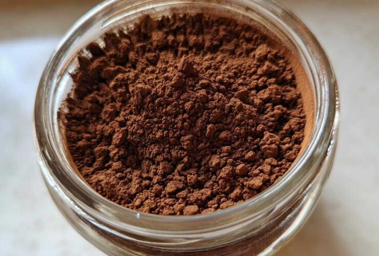 Overhead close-up of rich brown homemade hot cocoa mix powder filling a clear glass jar.