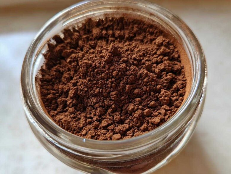 Overhead close-up of rich brown homemade hot cocoa mix powder filling a clear glass jar.