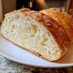 Close-up of the airy, open crumb structure inside a freshly baked loaf of Italian bread.