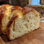 Close-up of a freshly baked loaf of Italian bread, showing a golden-brown crust and soft, airy interior.