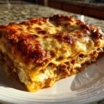 A thick, golden-brown slice of Lasagna with Cottage Cheese showing layers of pasta, meat sauce, and white cheese filling.