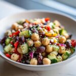 Close-up of a fresh Mediterranean bean salad featuring chickpeas, cucumbers, olives, and feta cheese.