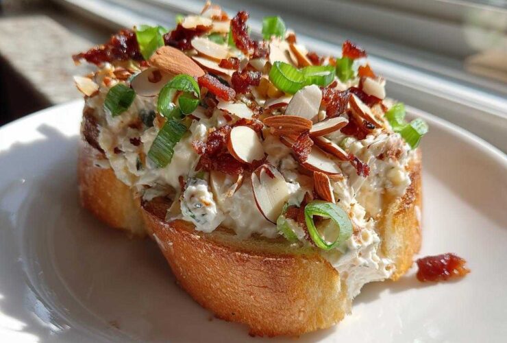 A thick layer of creamy Neiman Marcus dip topped with slivered almonds, bacon bits, and green onions on toasted bread.