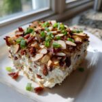 A square serving of creamy Neiman Marcus Dip topped generously with sliced almonds, crumbled bacon, and chopped green onions.