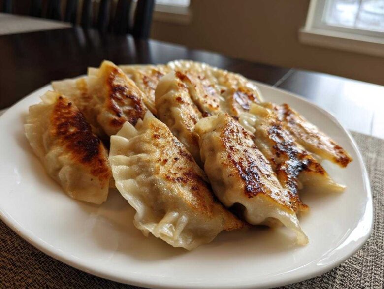 A plate of golden-brown, pan-fried Traditional Chinese Dumplings with crispy bottoms.