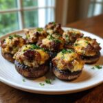 A plate of perfectly baked sausage stuffed mushrooms topped with melted cheese and fresh parsley.