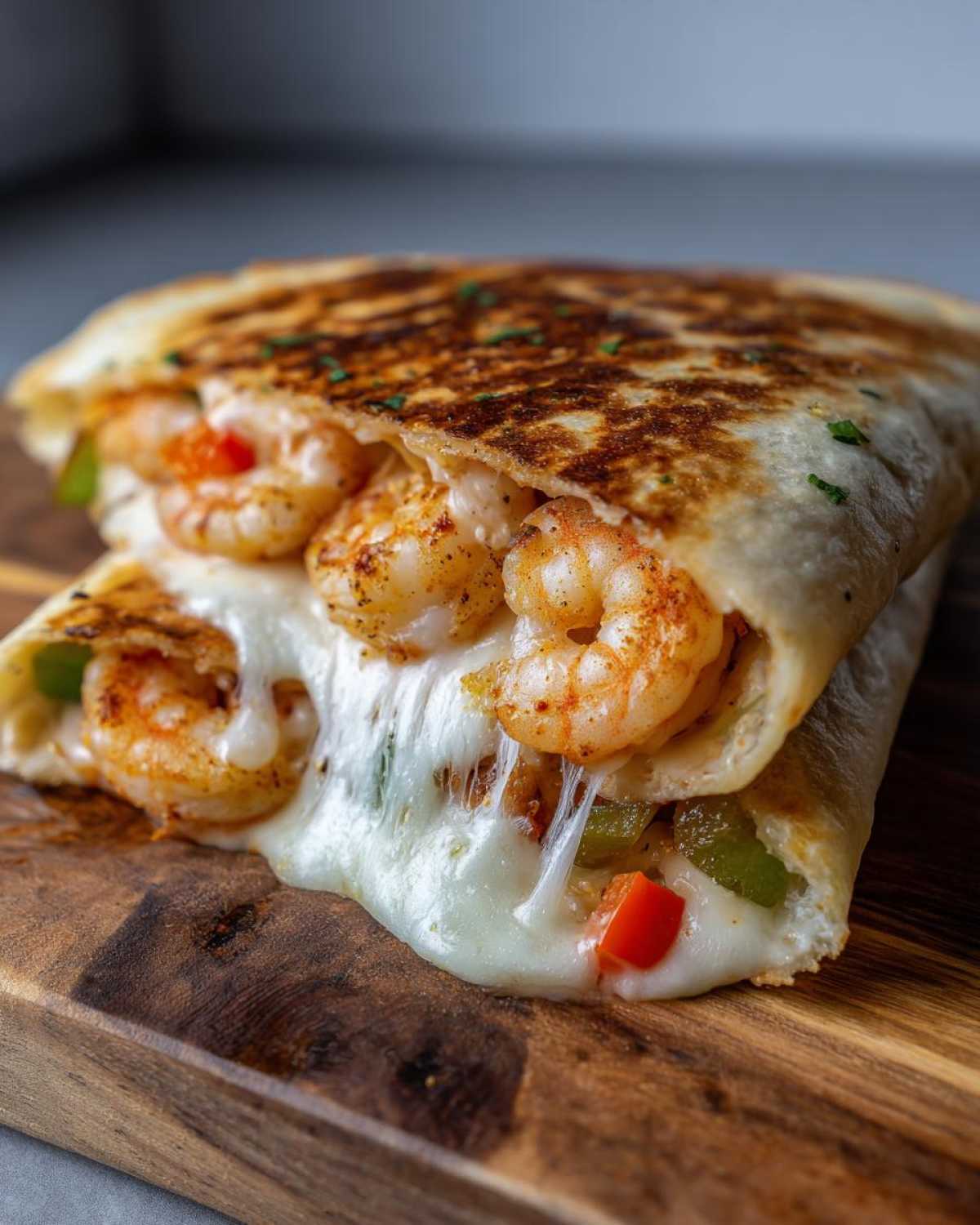 Close-up of a perfectly grilled shrimp quesadilla oozing melted cheese, filled with seasoned shrimp and peppers.
