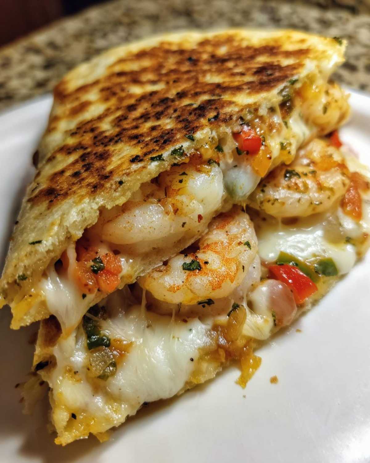 Close-up of a perfectly grilled shrimp quesadilla slice oozing with melted white cheese and seasoned shrimp.