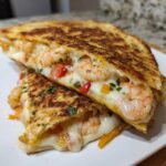 Close-up of a perfectly grilled shrimp quesadilla cut in half, showing melted cheese and seasoned shrimp inside.