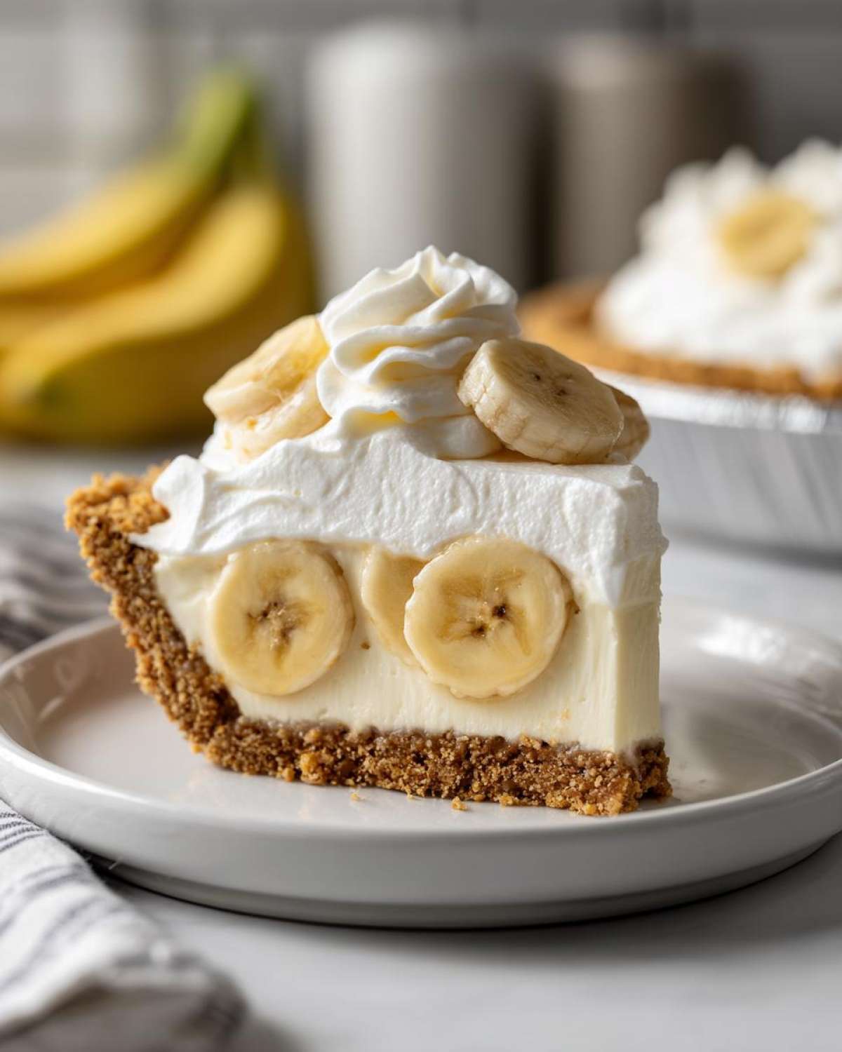 A delicious slice of banana cream pie recipe showing graham cracker crust, creamy filling, and whipped topping with banana slices.