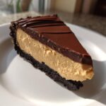 A perfect slice of peanut butter pie with a chocolate crust, creamy filling, and chocolate ganache topping.