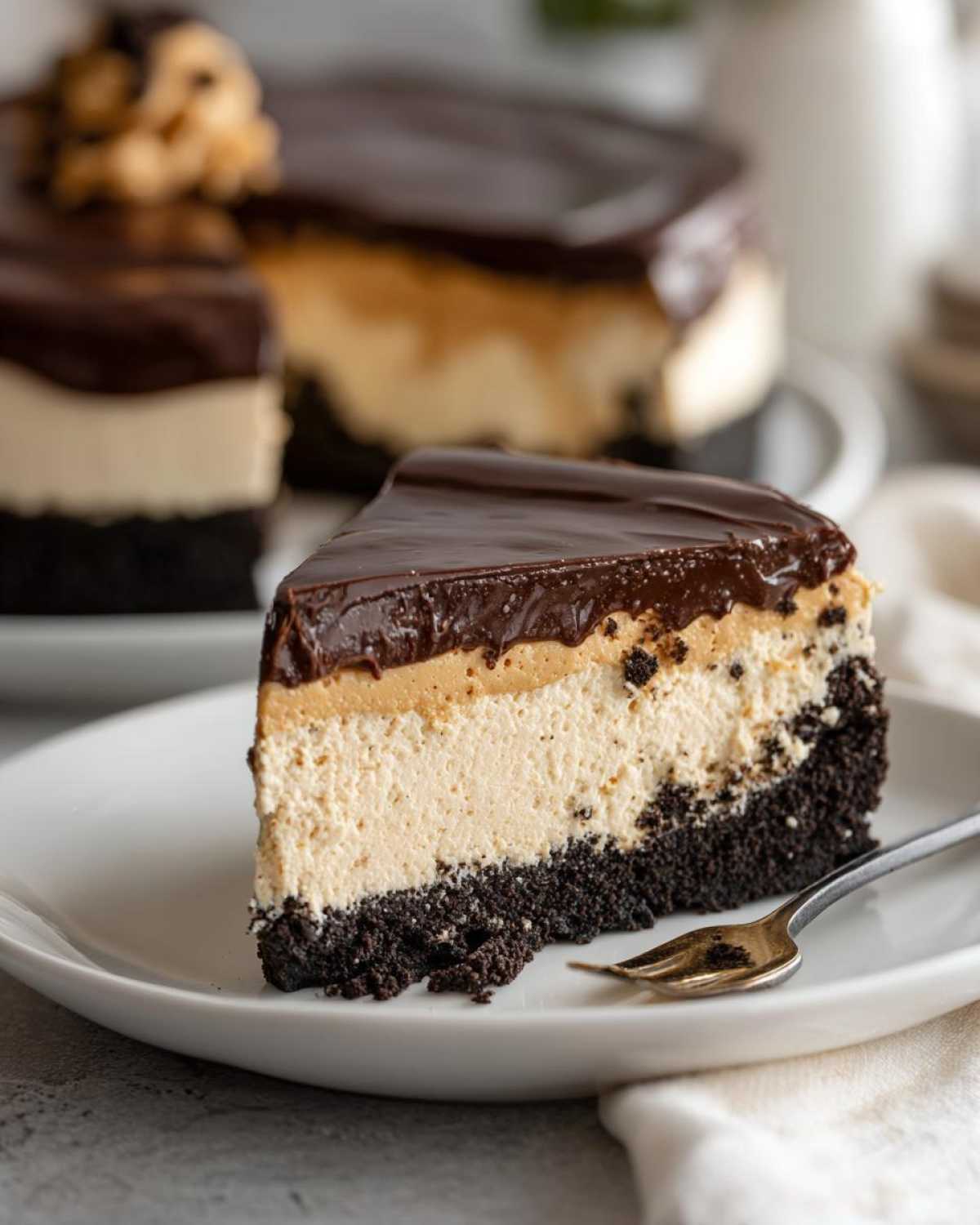 A decadent slice of peanut butter pie with a dark crust, creamy filling, peanut butter layer, and chocolate ganache topping.