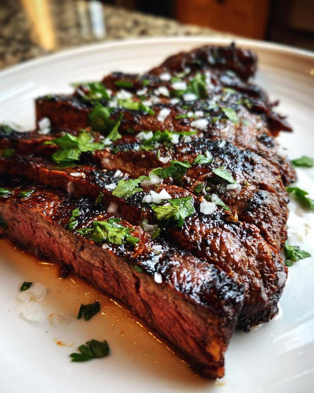 Close-up of sliced, juicy carne asada steak showing a medium-rare center, topped with cilantro and onion, prepared with carne asada marinade.