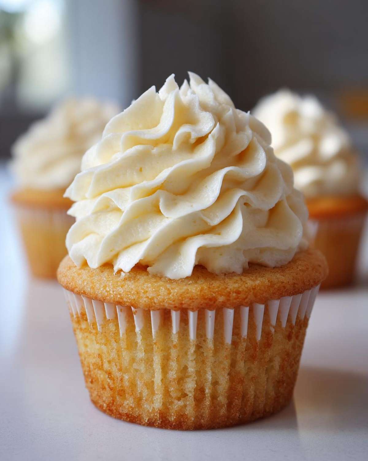 Close-up of a single, perfectly baked vanilla cupcakes topped with a swirl of creamy white frosting.