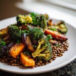 Close-up of roasted broccoli and carrots served over a bed of brown lentils, part of a veggie lentil salad.