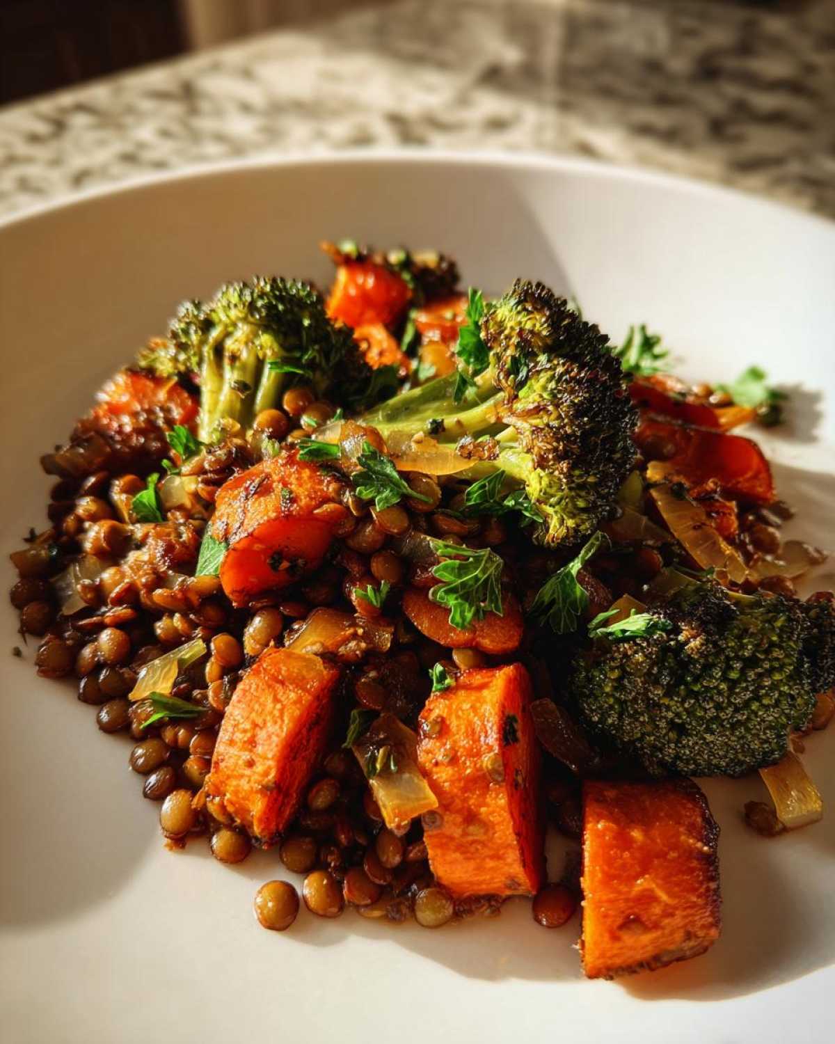 Close-up of a hearty veggie lentil salad featuring brown lentils, roasted sweet potatoes, and charred broccoli florets.