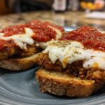 Two servings of crispy Air Fryer Chicken Parmesan topped with melted mozzarella and marinara sauce, served on toasted bread.