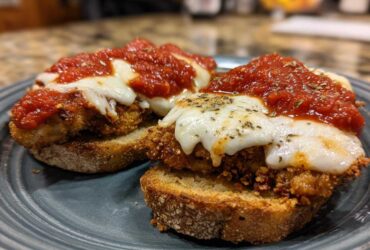 Two servings of crispy Air Fryer Chicken Parmesan topped with melted mozzarella and marinara sauce, served on toasted bread.