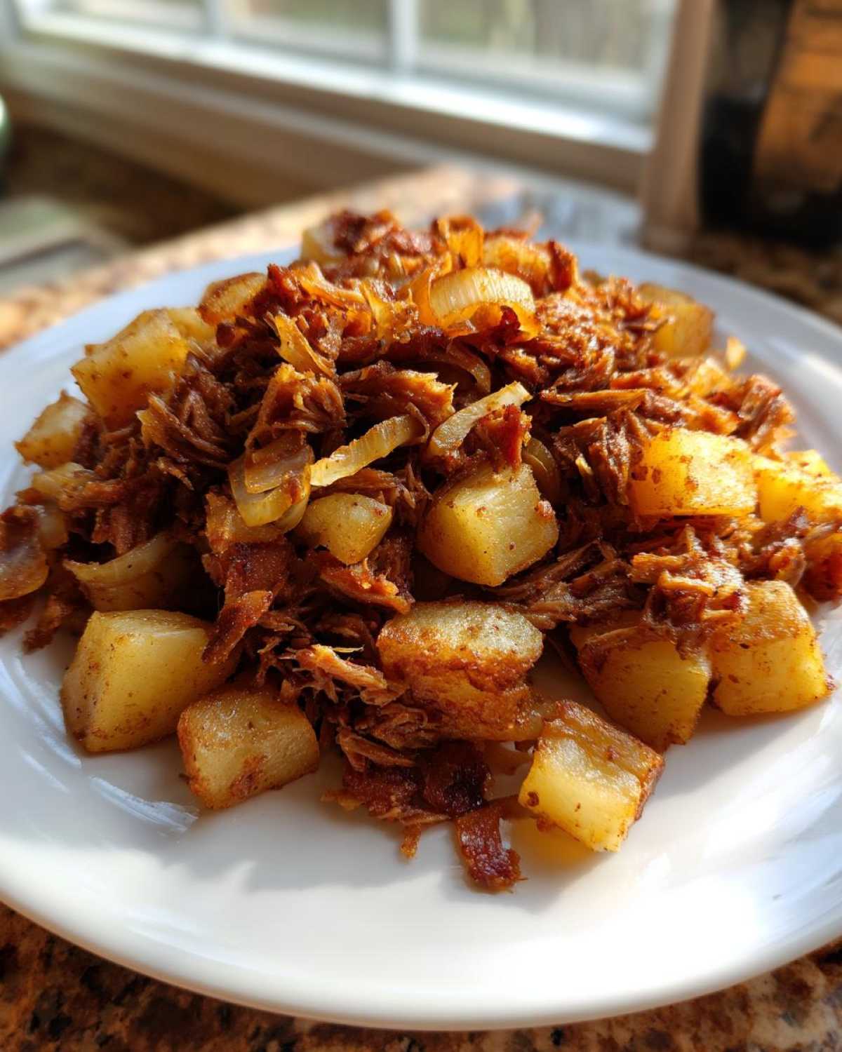 A plate of golden, crispy Air Fryer Corned Beef Hash mixed with chunks of potatoes and caramelized onions.