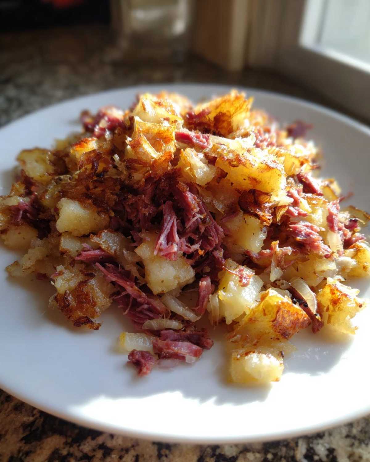 Close-up of crispy Air Fryer Corned Beef Hash with golden potatoes and shredded corned beef on a white plate.