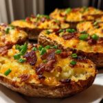 Close-up of several Air Fryer Crispy Potato Skins topped with melted cheddar cheese, bacon bits, and fresh chives.