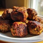 A close-up of several golden-brown, crispy Air Fryer Italian Meatballs piled high on a white plate.