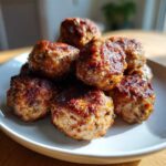 A close-up stack of golden-brown, perfectly cooked Air Fryer Italian Meatballs resting on a white plate.