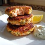 A stack of three golden brown Air Fryer Salmon Patties, with the top one broken open to show the flaky pink interior.