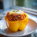 A single yellow Air Fryer Stuffed Bell Peppers, generously filled with meat and rice, topped with melted cheese.