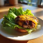 A juicy Air Fryer Turkey Burger topped with melted cheddar cheese served on lettuce on a white plate.