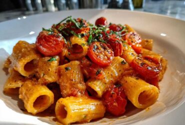 Close-up of creamy Baked Feta Pasta with roasted cherry tomatoes and fresh basil.