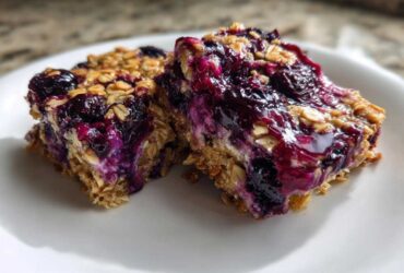 Close-up of two moist Blueberry Baked Oatmeal Squares featuring oats and rich, purple blueberry topping.