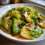 Close-up of vibrant green Cabbage Stir Fry with Garlic Ginger Sauce glistening on a white plate.