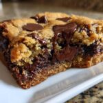 Close-up of a thick, gooey Chewy Chocolate Chip Cookie Bars square with melted chocolate oozing out.