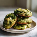 A stack of four vibrant green Chewy Matcha White Chocolate Cookies with visible white chocolate chunks.