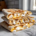 Stack of three chicken quesadilla wedges oozing with melted cheese and Copycat Taco Bell Chicken Quesadilla Sauce.