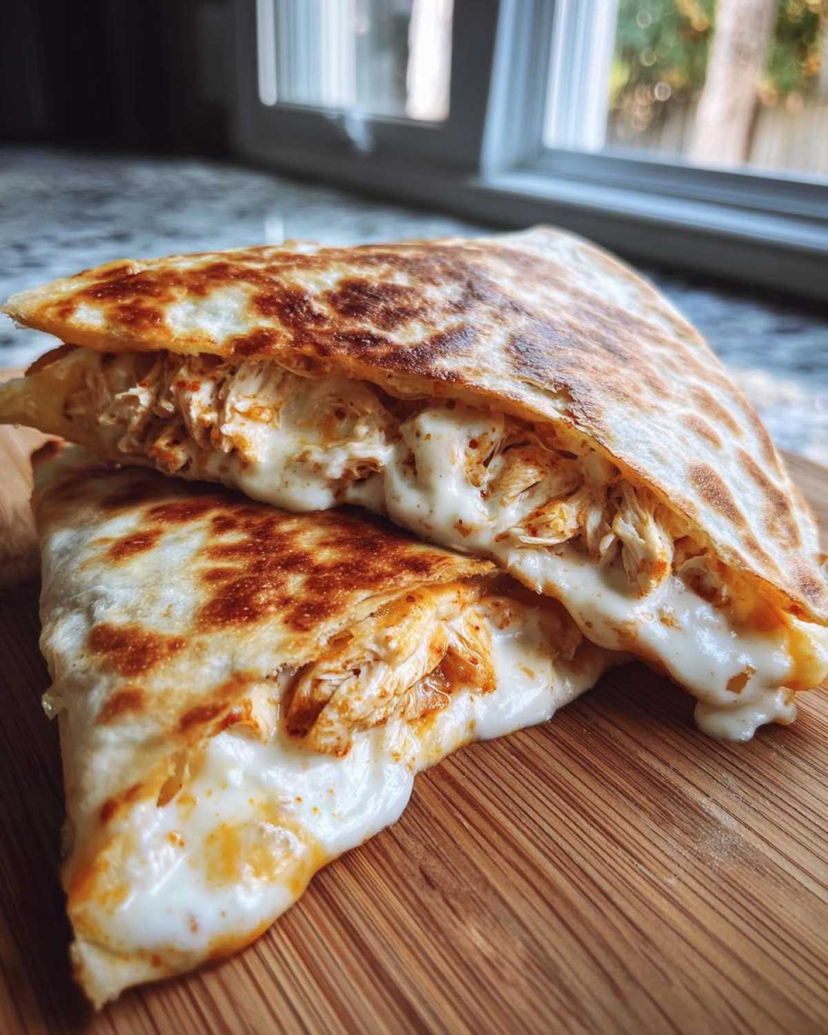 Two halves of a grilled chicken quesadilla oozing with melted cheese and sauce, made with Copycat Taco Bell Chicken Quesadilla Sauce.