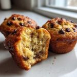 Close-up of moist Chocolate Chip Banana Muffins, one cut in half showing the soft interior texture.