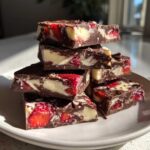 A stack of rich Chocolate Covered Strawberry Bark pieces showing dark chocolate, white filling, and bright red strawberries.